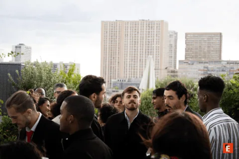 Personnes en terrasse sur toit urbain, réception conviviale avec horizon et végétation.