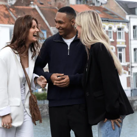 Trois amis rient sur une promenade au bord du canal urbain, style décontracté.