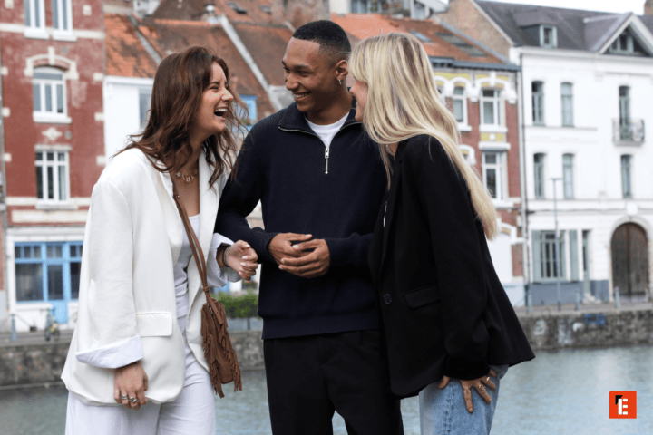 Trois amis rient sur une promenade au bord du canal urbain, style décontracté.