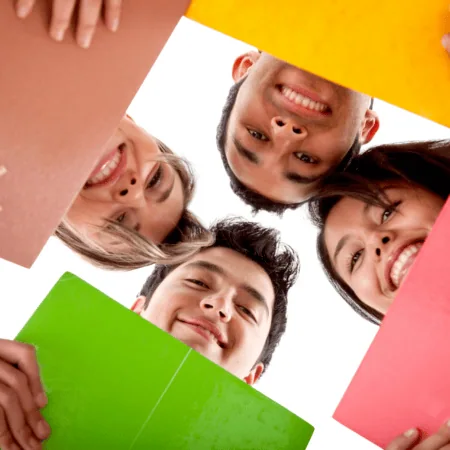 Jeunes étudiants souriants en cercle tenant dossiers colorés, collaboration et travail déquipe.