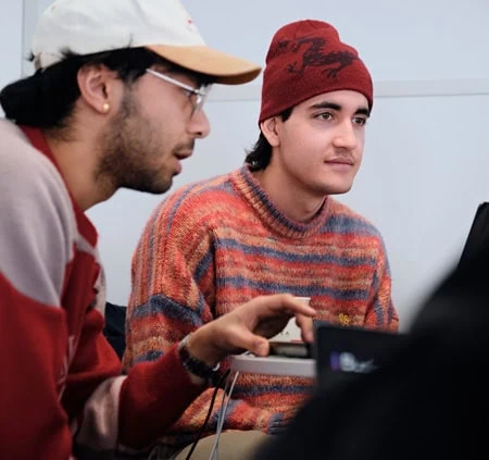 Deux jeunes collaborent sur ordinateur lors dune séance détude en groupe.