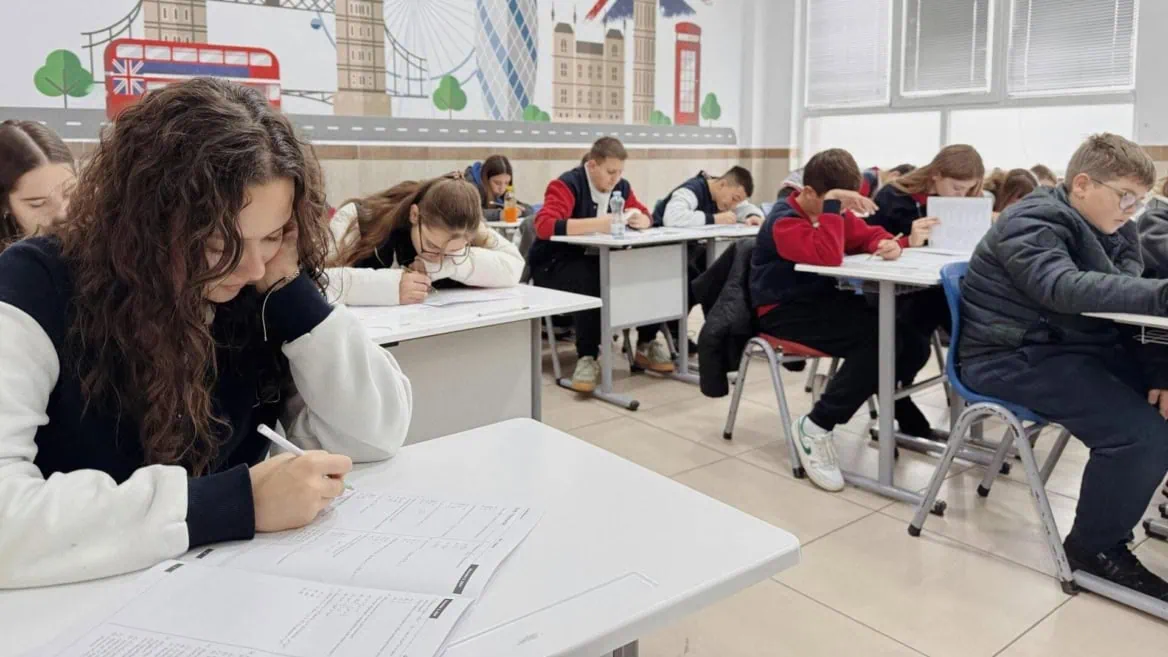 Élèves en examen dans une salle de classe moderne, concentrés à leur bureau.
