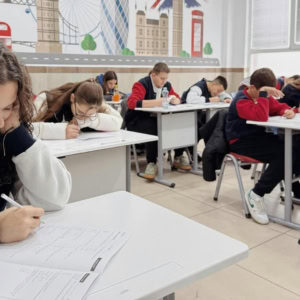 Élèves en examen dans une salle de classe moderne, concentrés à leur bureau.