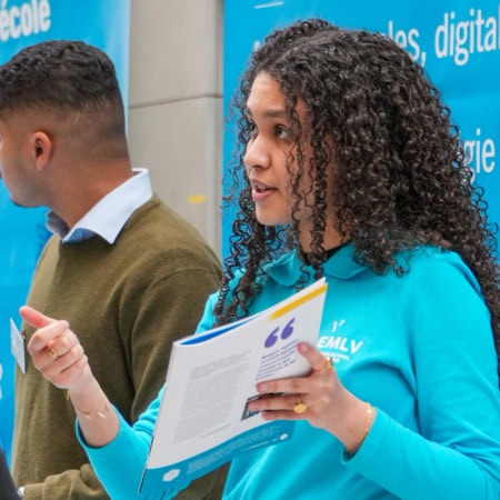 Équipe au stand dinformation, conseillère présentant une brochure lors dun salon universitaire.