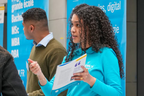 Équipe au stand dinformation, conseillère présentant une brochure lors dun salon universitaire.