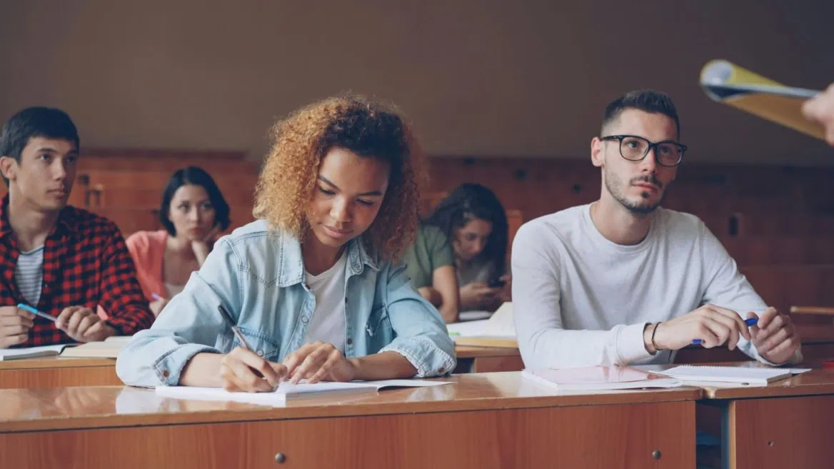 Étudiants en amphithéâtre prenant des notes pendant un cours universitaire.