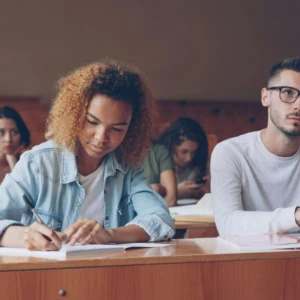 Étudiants en amphithéâtre prenant des notes pendant un cours universitaire.