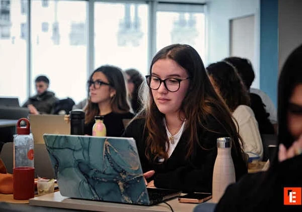 Étudiante concentrée sur son ordinateur portable dans une salle détude collective.