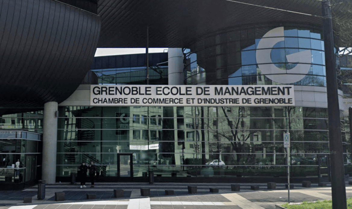 Façade de Grenoble École de Management en verre avec toit incliné et logo bleu.
