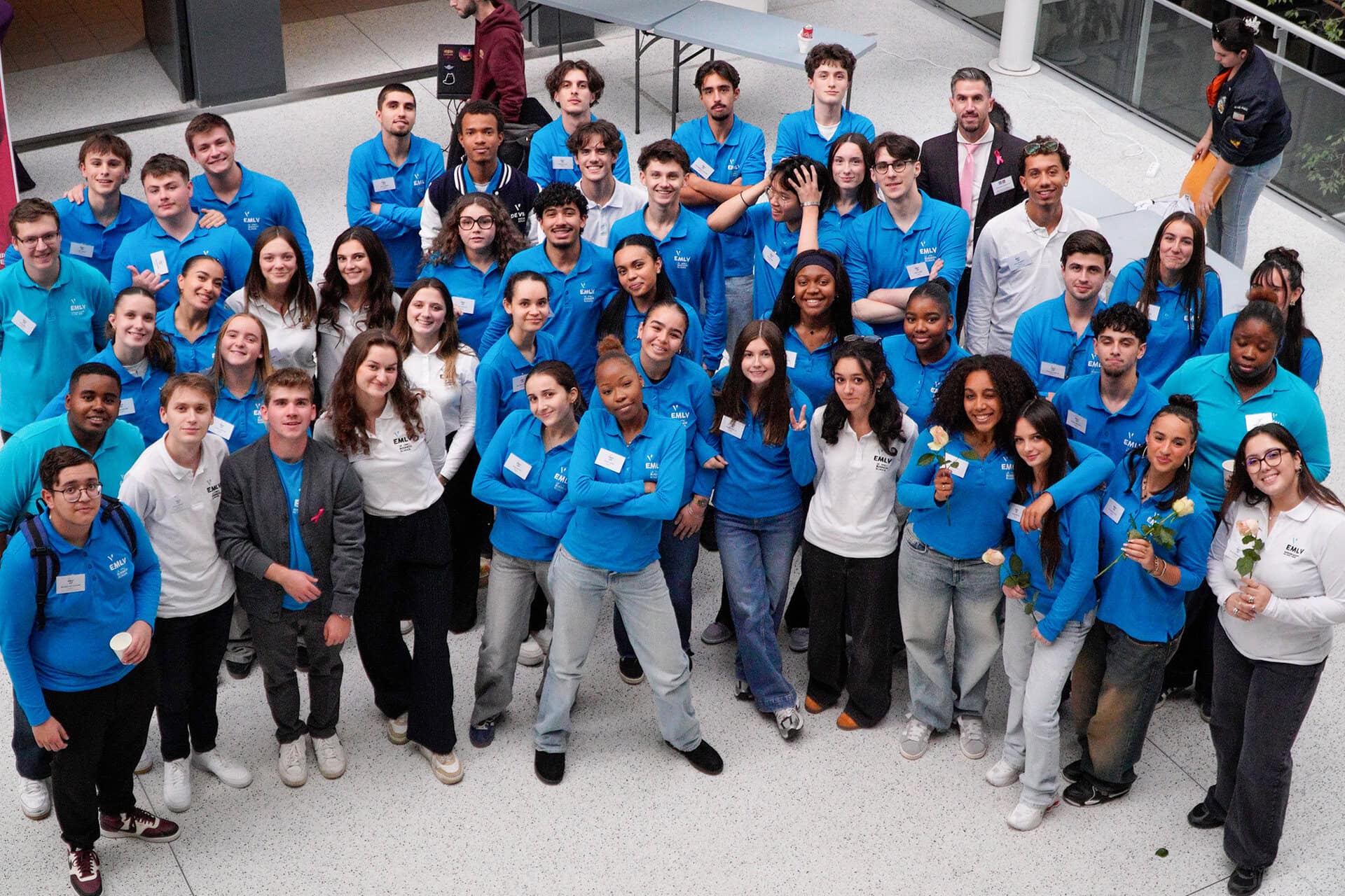 Photo aérienne du groupe détudiants EMLV en polos bleus dans latrium.