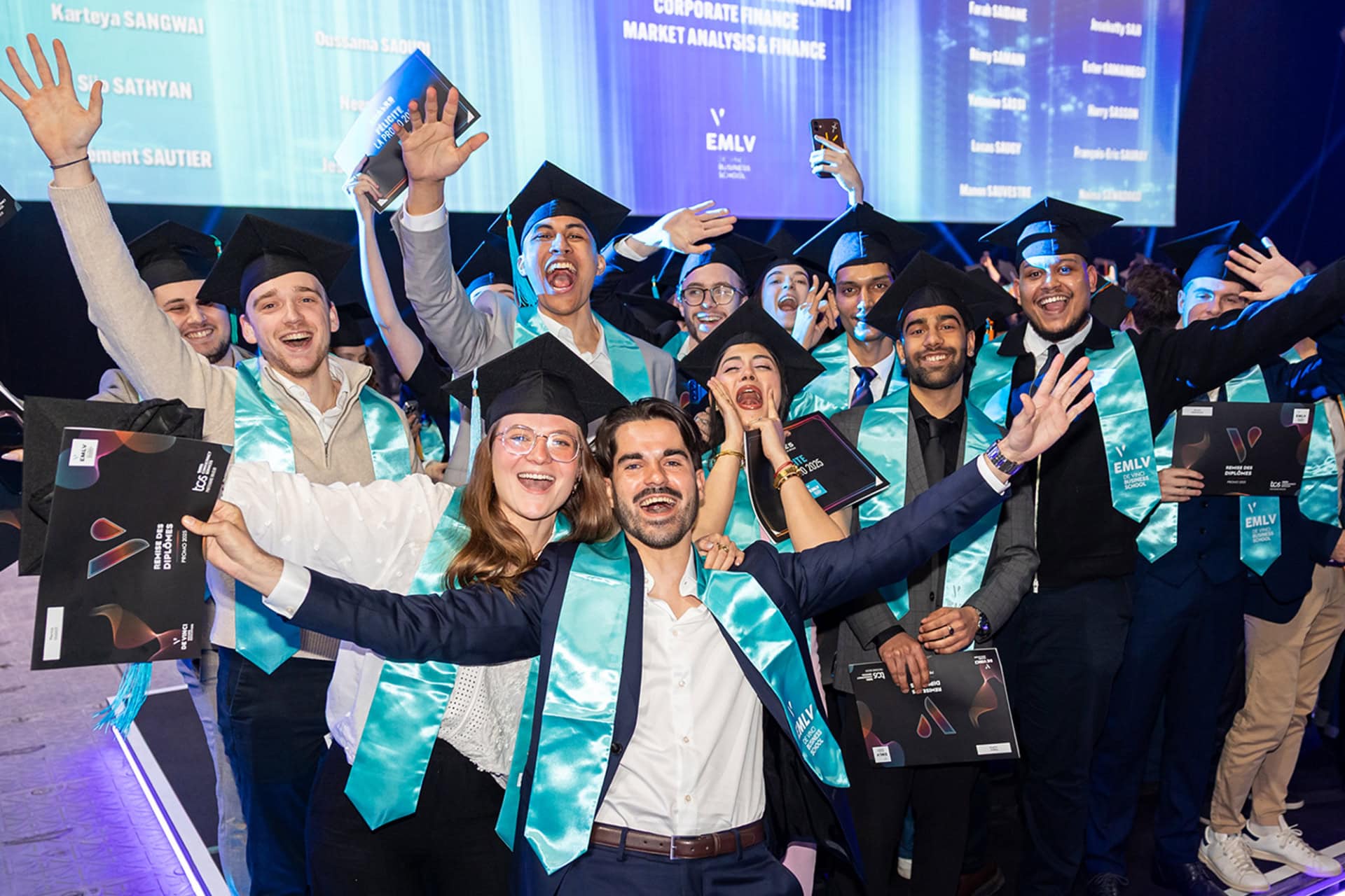 Remise de diplômes : grand groupe détudiants en toques et écharpes turquoises célébrant.