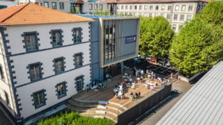 Terrasse ensoleillée du campus de Clermont École de Commerce, bâtiment historique et extension moderne.