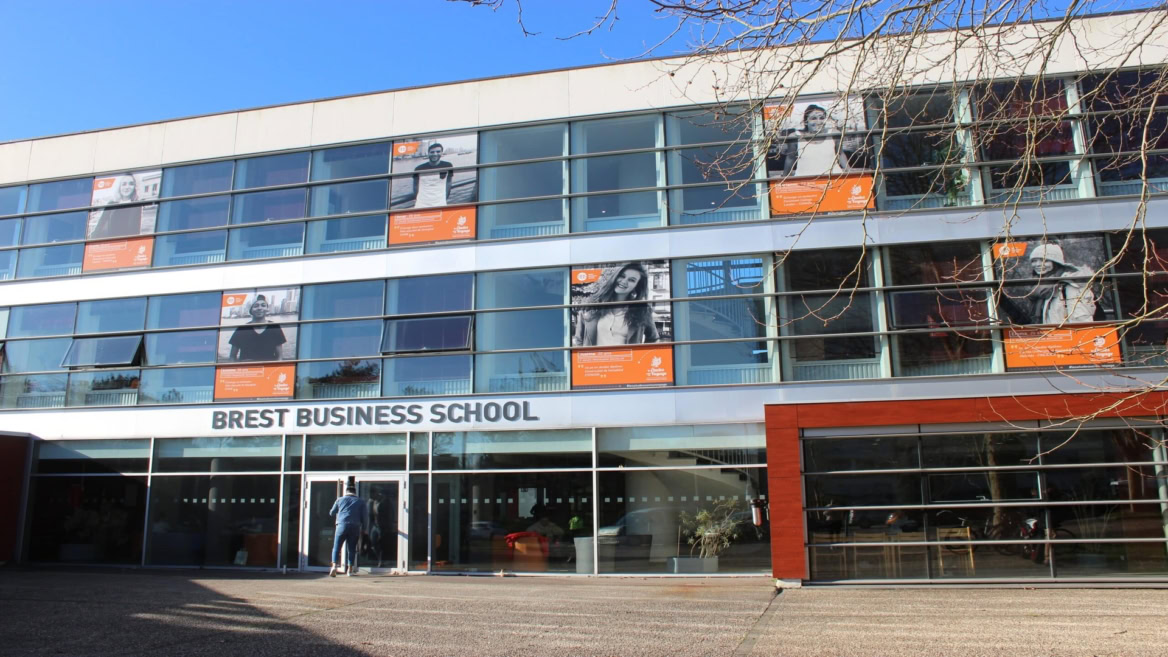 Façade moderne de Brest Business School avec entrée vitrée et affiches étudiantes.