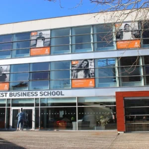 Façade moderne de Brest Business School avec entrée vitrée et affiches étudiantes.
