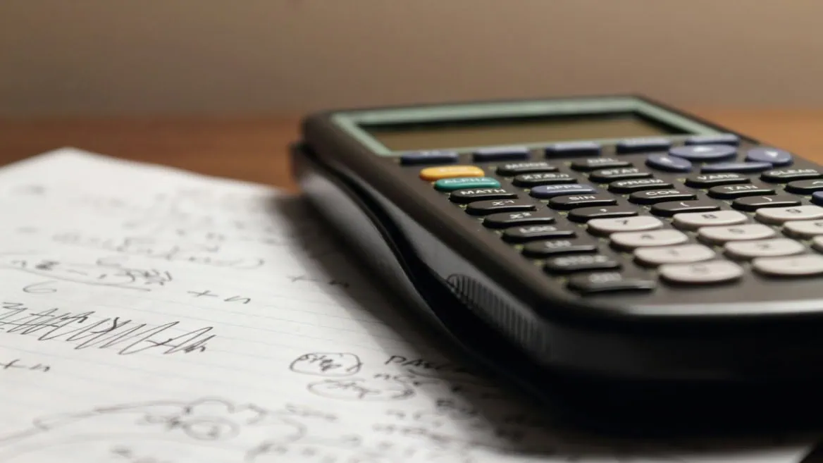 Calculatrice scientifique noire sur papier à lignes, notes manuscrites et calculs.