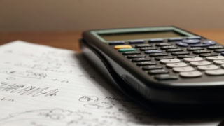 Calculatrice scientifique noire sur papier à lignes, notes manuscrites et calculs.