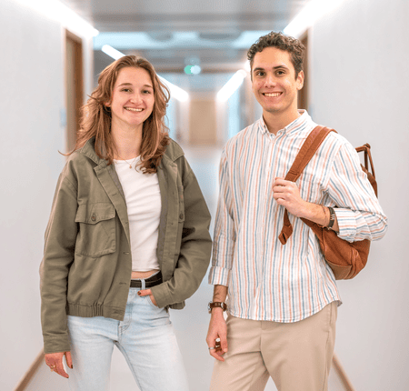Couple souriant dans un couloir moderne et lumineux, ambiance décontractée.