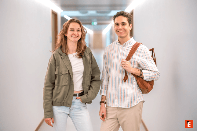 Couple souriant dans un couloir moderne et lumineux, ambiance décontractée.