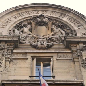 Façade de l’École Nationale dArts et Métiers, tympan sculpté en pierre, drapeau français.