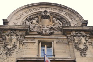 Façade de l’École Nationale dArts et Métiers, tympan sculpté en pierre, drapeau français.