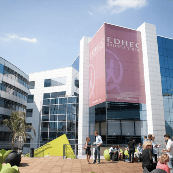 Campus EDHEC moderne, terrasse ensoleillée avec étudiants, bâtiments vitrés et mobilier coloré.