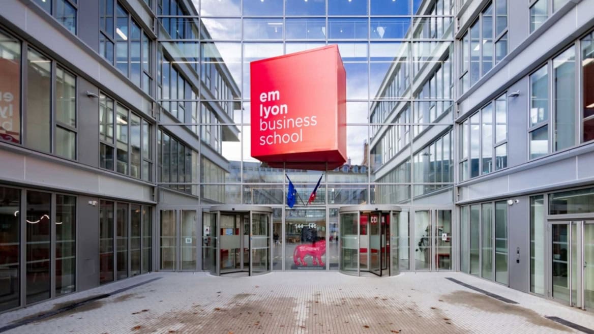 Façade moderne demlyon business school avec cube rouge et portes tournantes.