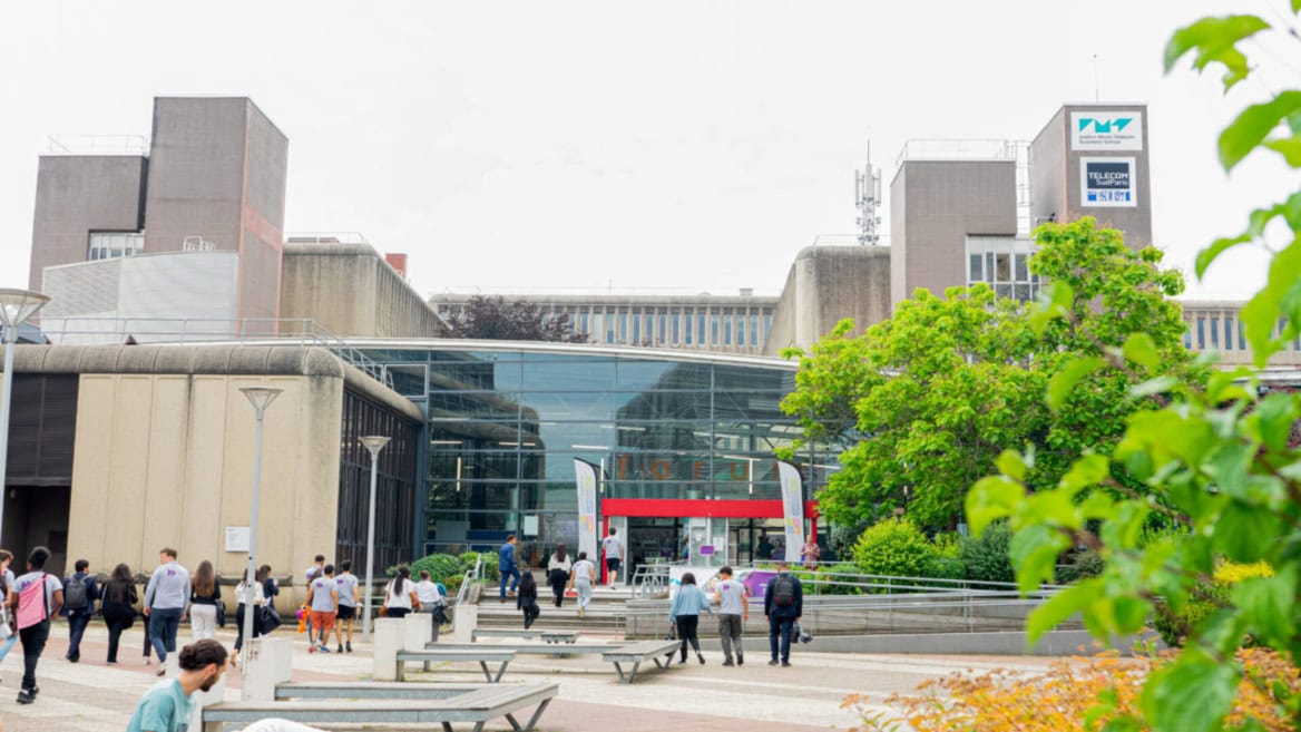 Entrée du campus Télécom SudParis, bâtiment brutaliste avec atrium vitré.