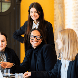 Équipe féminine en réunion collaborative autour dun ordinateur portable au bureau, sourires et travail déquipe.