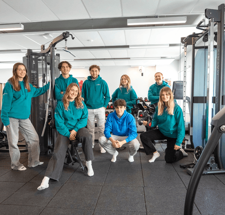 Portrait déquipe de jeunes adultes en sweats à capuche dans une salle de sport moderne.