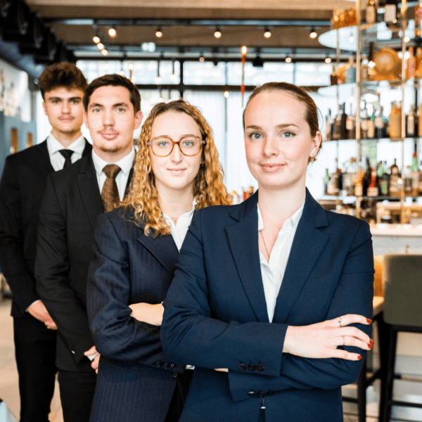 Équipe professionnelle dhôtel en uniforme devant bar moderne, personnel de service attentif.