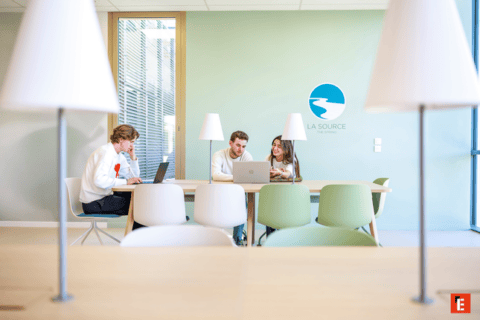 Espace de coworking lumineux moderne avec personnes collaborant sur ordinateurs portables.