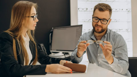 Essai de lunettes et verres en boutique doptique, opticien conseillant un client.