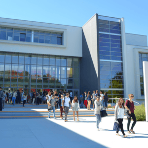 Entrée du campus ESSCA, bâtiment moderne vitré avec étudiants et cour ensoleillée.