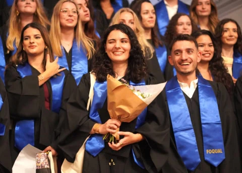 Photo de groupe détudiants diplômés en stoles bleues souriants, cérémonie.