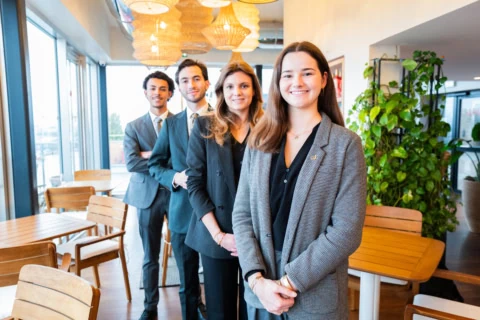 Groupe de jeunes professionnels en café coworking lumineux, équipe business moderne et conviviale.