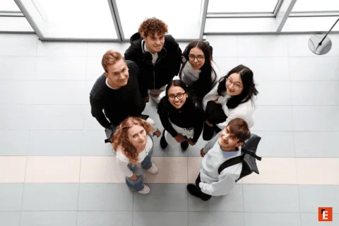 Groupe de sept personnes regardant vers le haut dans un espace intérieur lumineux.