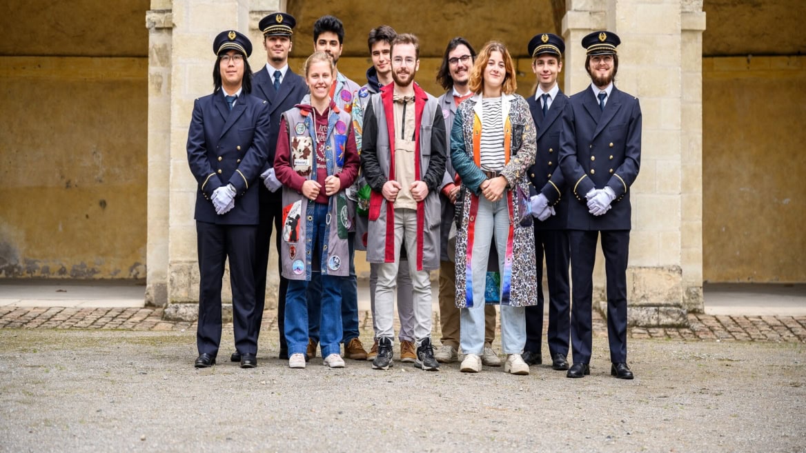 Portrait de groupe de dix jeunes sous arcade : uniformes bleus et tenues décontractées colorées.