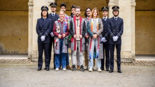 Portrait de groupe de dix jeunes sous arcade : uniformes bleus et tenues décontractées colorées.
