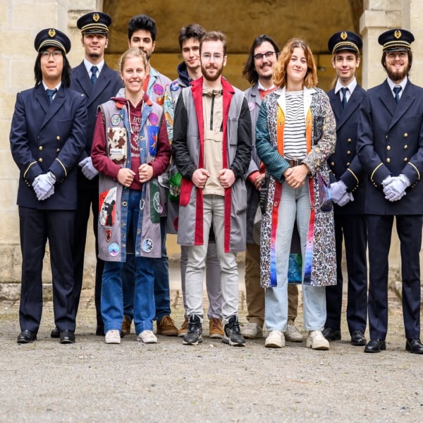 Portrait de groupe de dix jeunes sous arcade : uniformes bleus et tenues décontractées colorées.