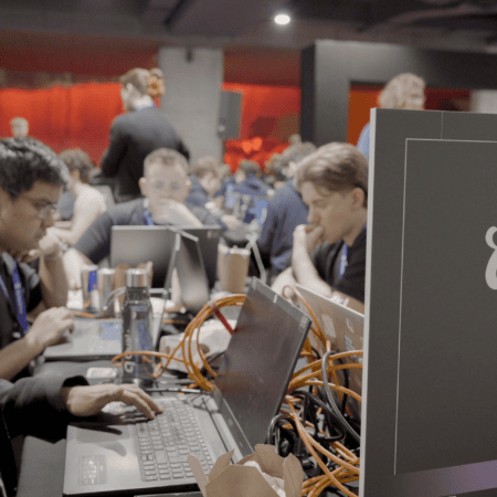 Hackathon : équipe concentrée sur ordinateurs portables, câbles et badges.