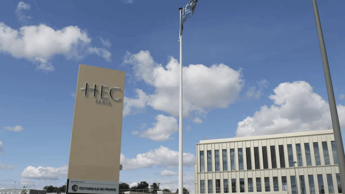 HEC Paris : panneau et bâtiment du campus sous ciel bleu.