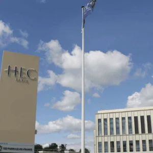 HEC Paris : panneau et bâtiment du campus sous ciel bleu.
