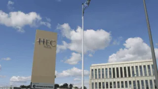 HEC Paris : panneau et bâtiment du campus sous ciel bleu.