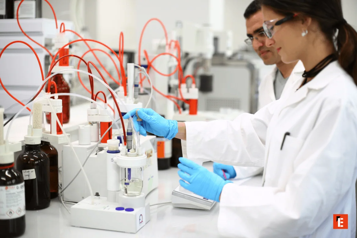 Laboratoire analytique moderne: technicien en gants manipulant électrode pour analyse chimique, tubulures rouges.