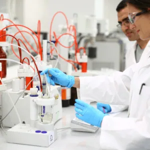 Laboratoire analytique moderne: technicien en gants manipulant électrode pour analyse chimique, tubulures rouges.
