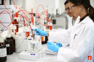 Laboratoire analytique moderne: technicien en gants manipulant électrode pour analyse chimique, tubulures rouges.