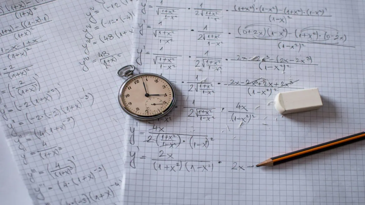 Montre à gousset sur papier millimétré couvert de calculs mathématiques, crayon et gomme.