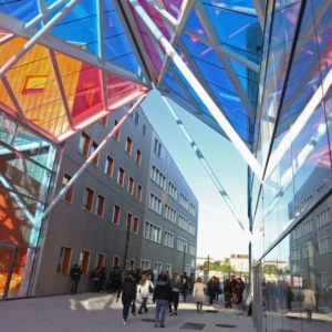 Passage urbain moderne à vitraux colorés, reflets en verre et flux de piétons.