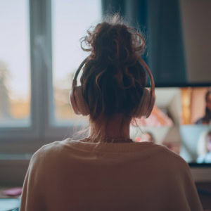 Personne en visioconférence au casque devant ordinateur, télétravail, bureau lumineux et concentration.