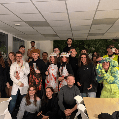 Photo de groupe au bureau pour Halloween : collègues déguisés en costumes effrayants et ludiques.